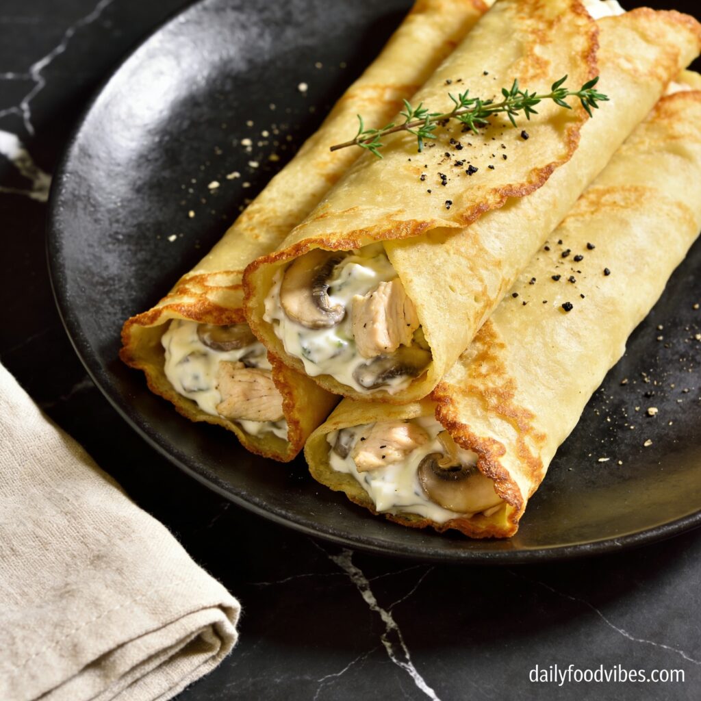 Beautifully plated healthy air fryer chicken and mushroom crepes with Greek yogurt on black marble countertop showing golden crispy texture
